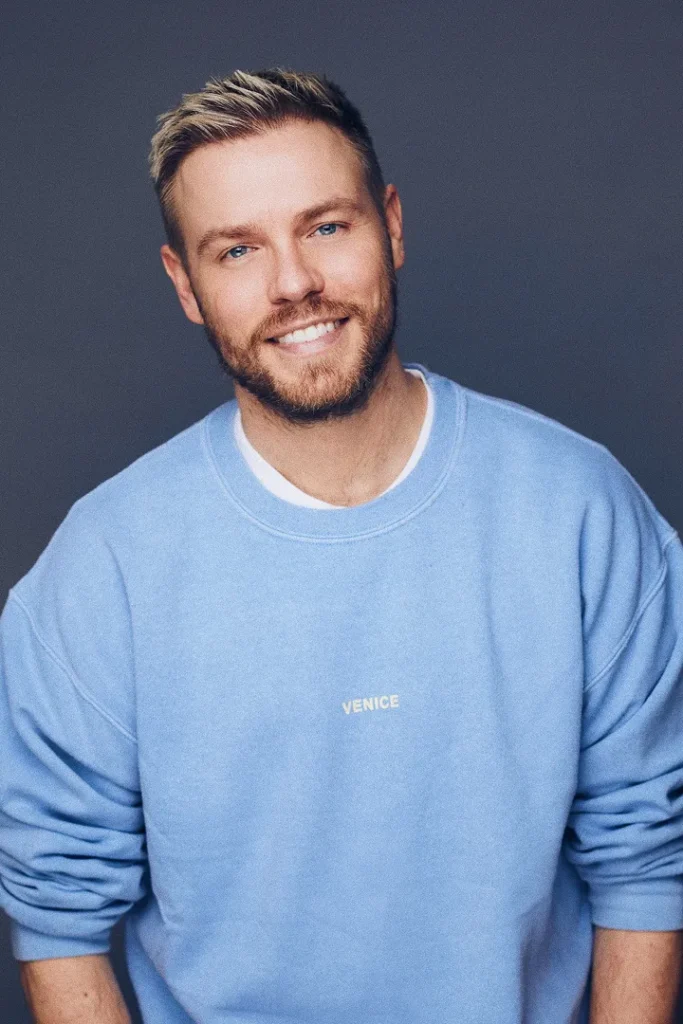 Ein Mann mit blonden Haaren lächelt.