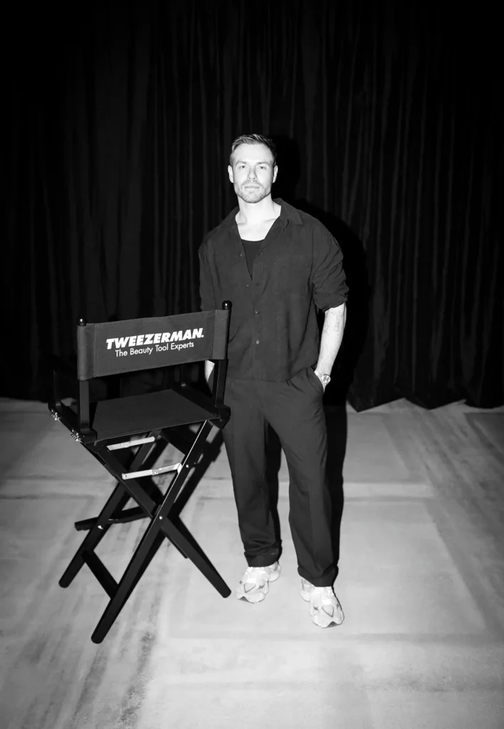 Mann steht neben einem Stuhl mit Tweezerman-Logo.
